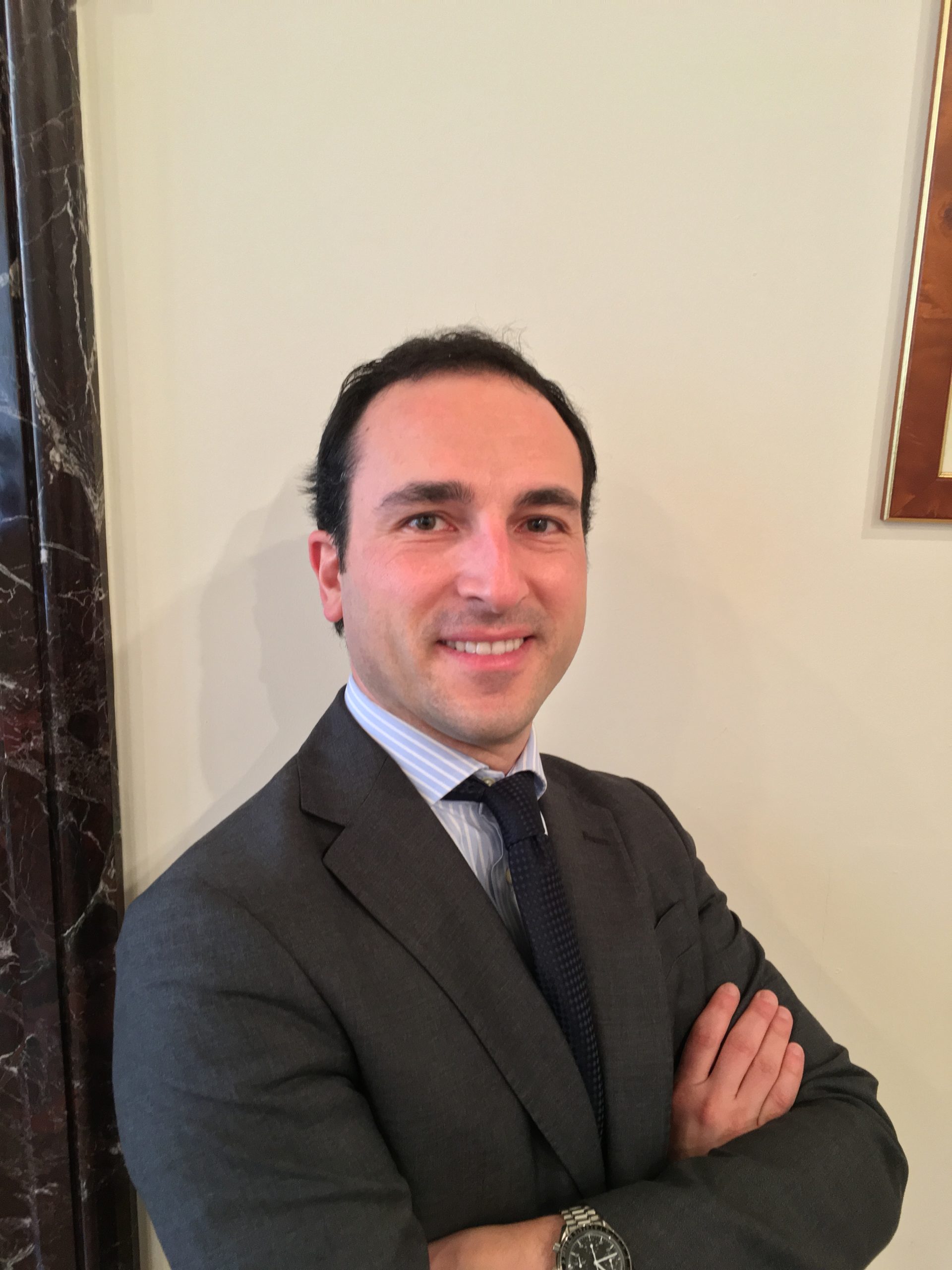 Lawyer posing confidently with arms crossed in a professional office setting.
