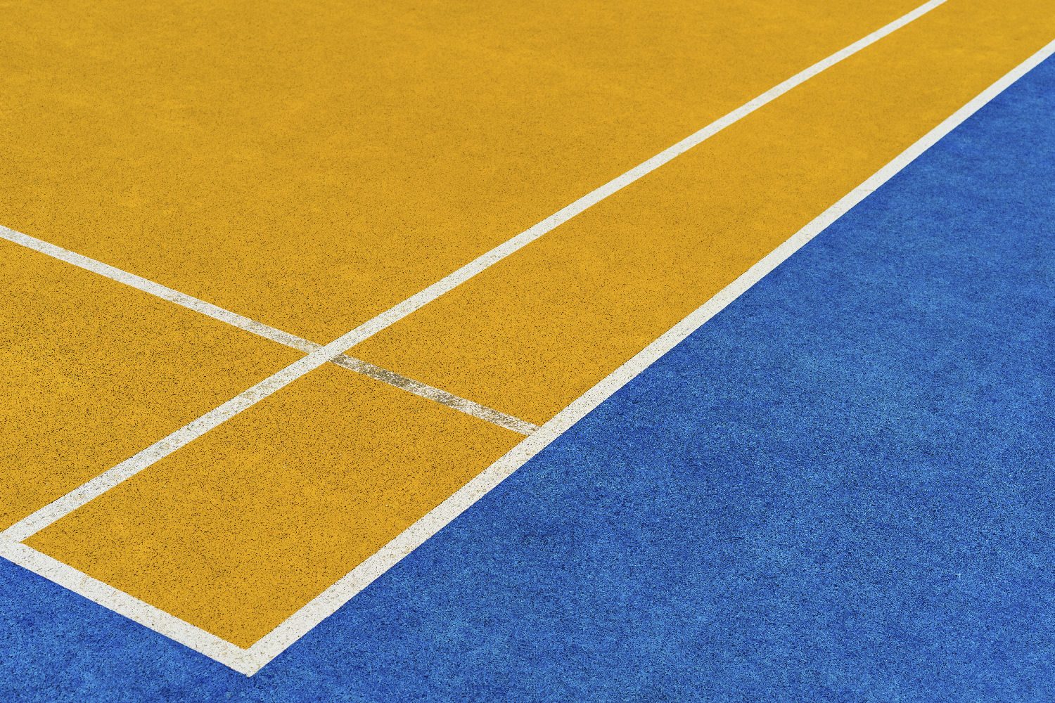 Tennis court surface with bright yellow and blue sections, featuring white boundary lines.