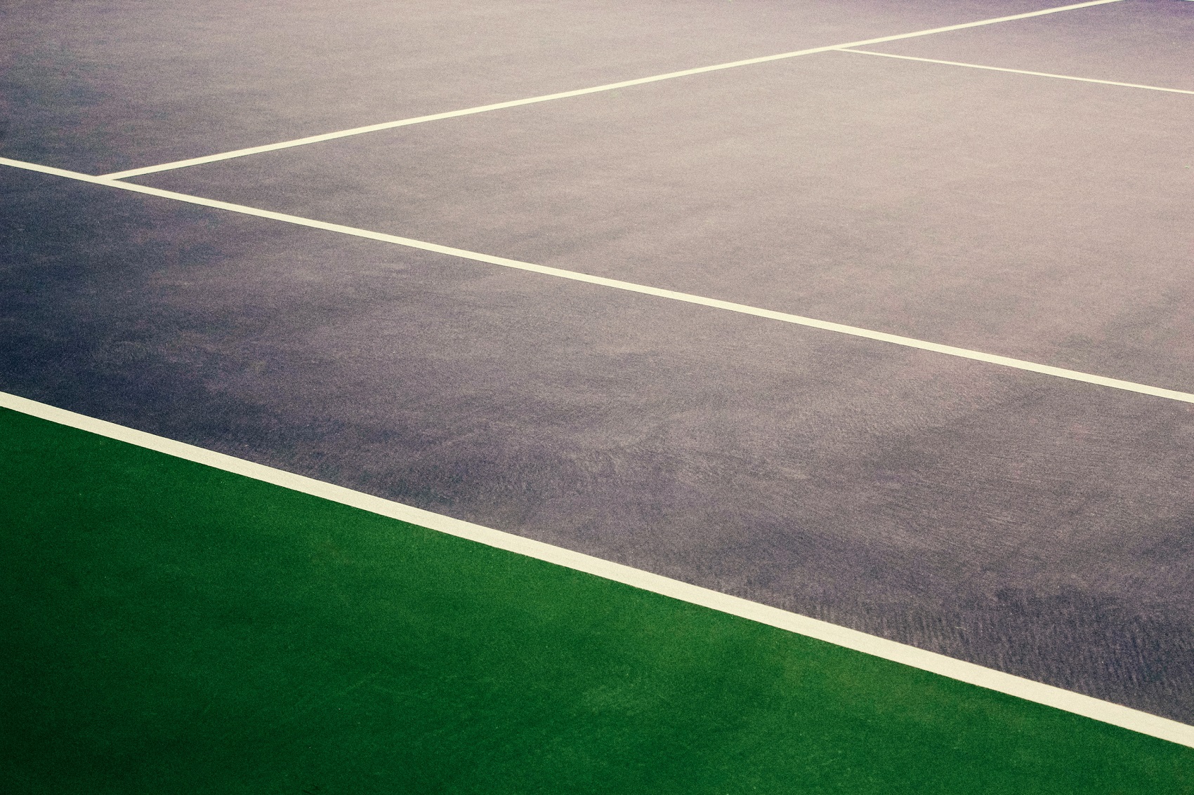Tennis court surface with blue and green sections and white boundary lines.