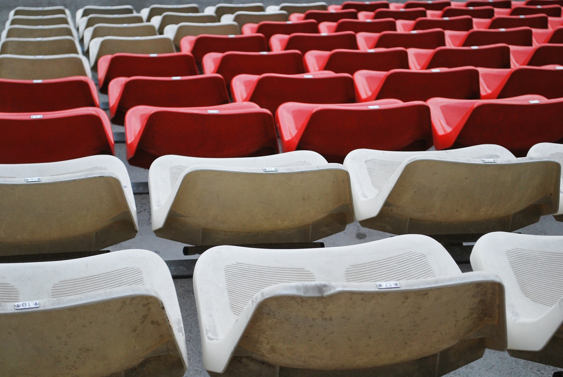 Rows of red and white stadium seats arranged in a zigzag pattern at a sports venue.