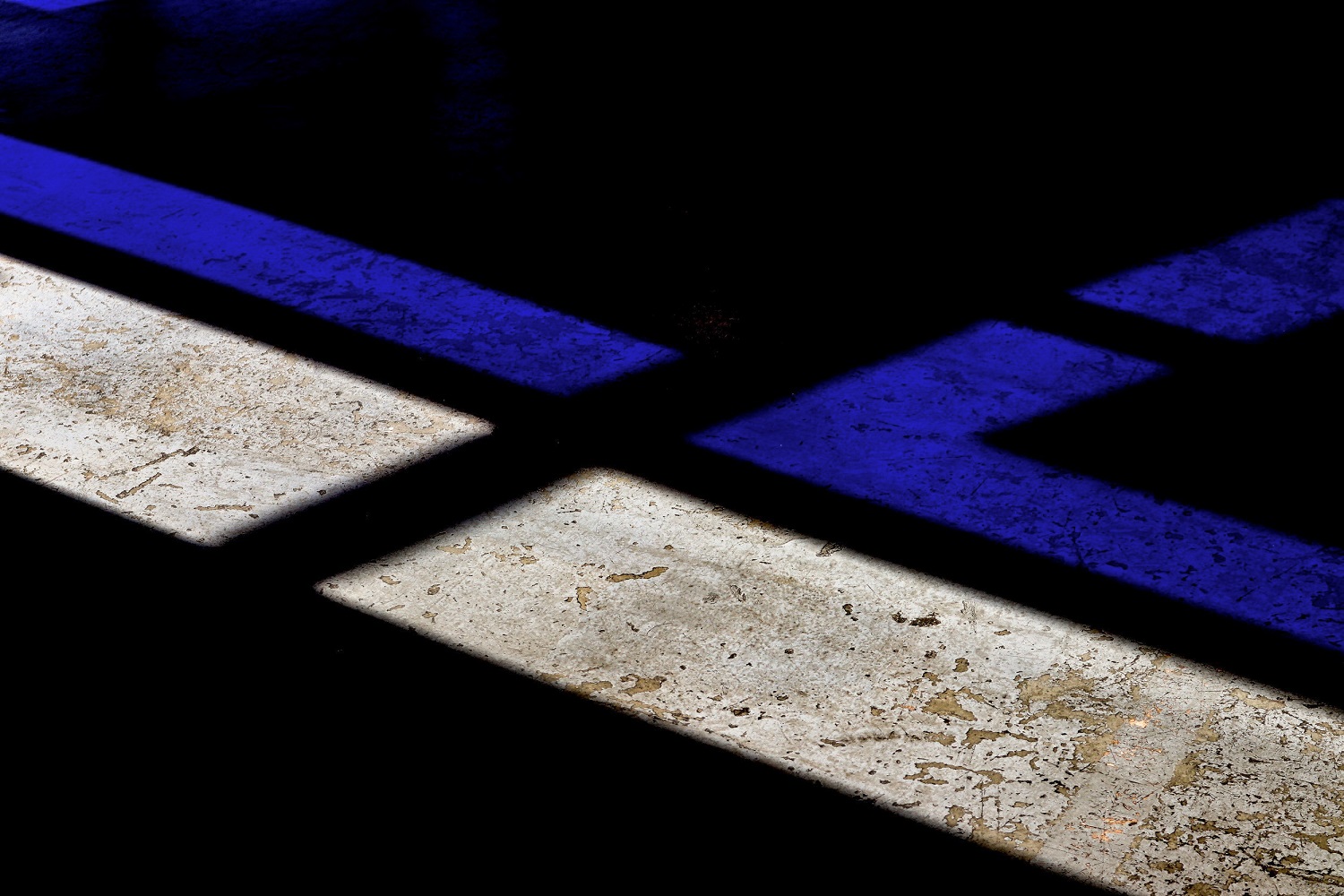 Blue and white light creating patterns on a textured surface in a dimly lit space.