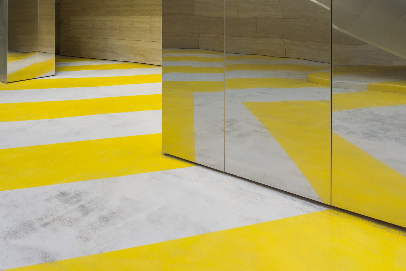 Abstract interior with yellow and white striped floor and reflective metallic surfaces.