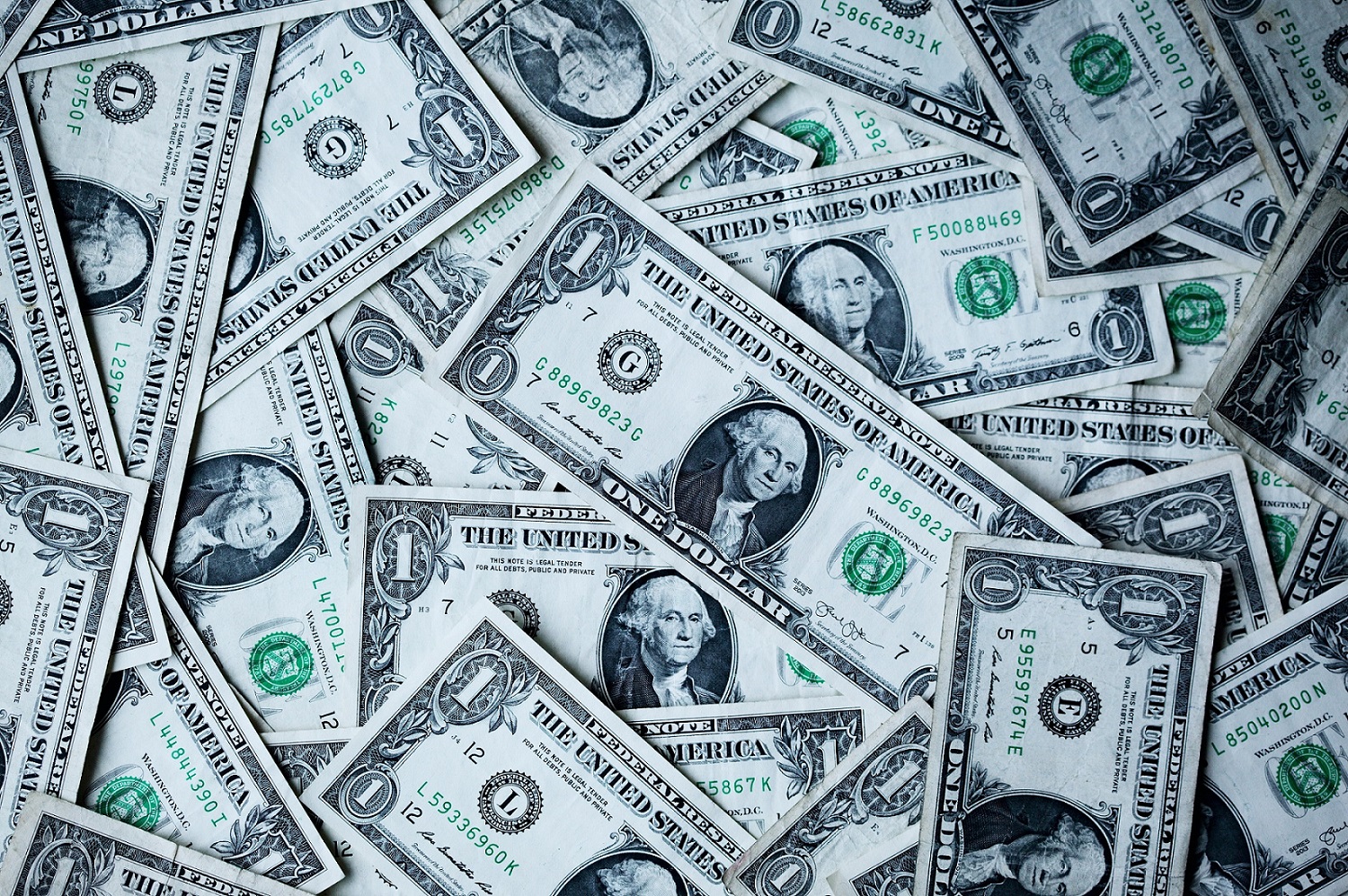 Scattered one-dollar bills covering a flat surface, illustrating currency and financial transactions.