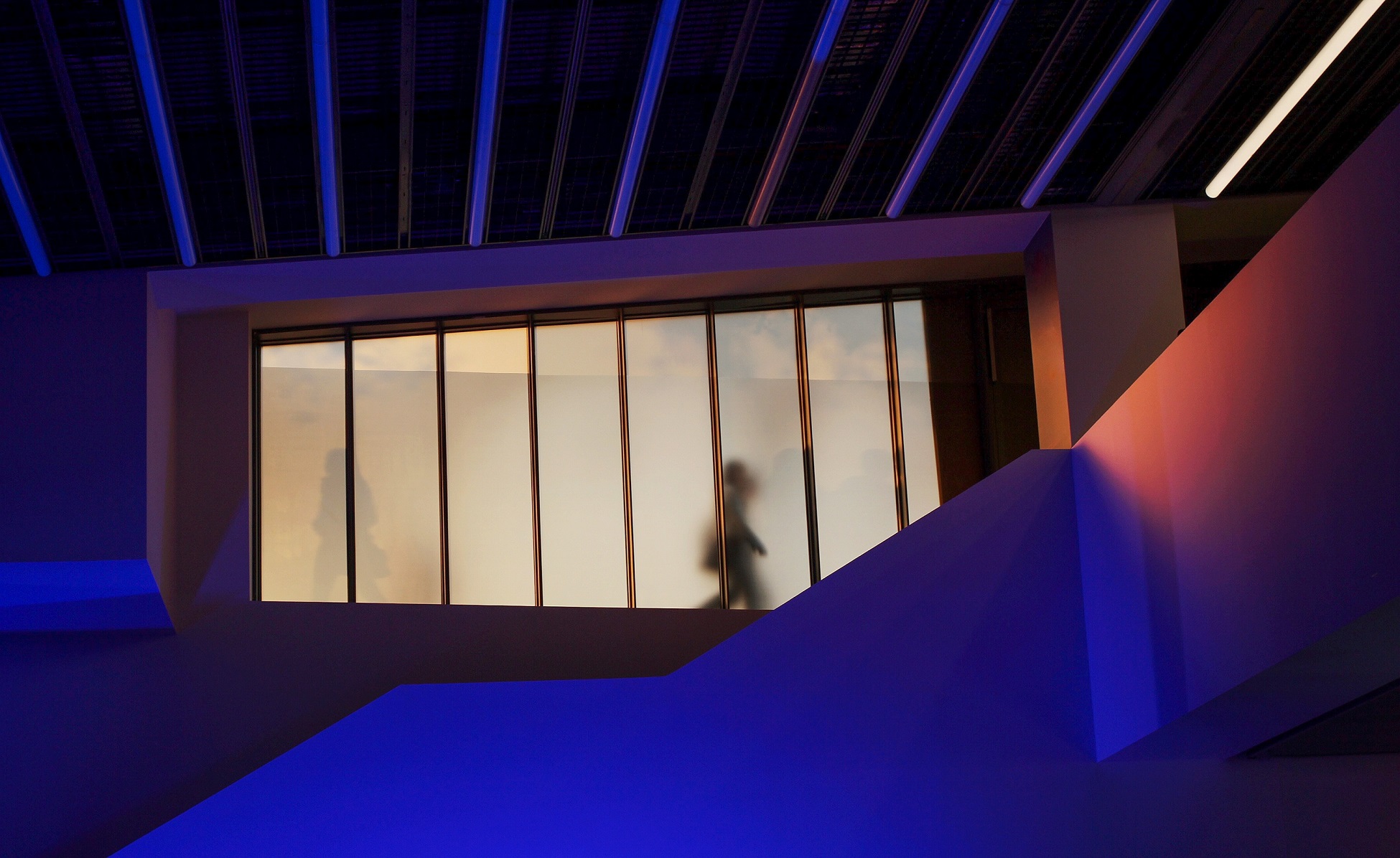 Silhouettes of individuals walking past frosted glass window in a contemporary legal office setting.