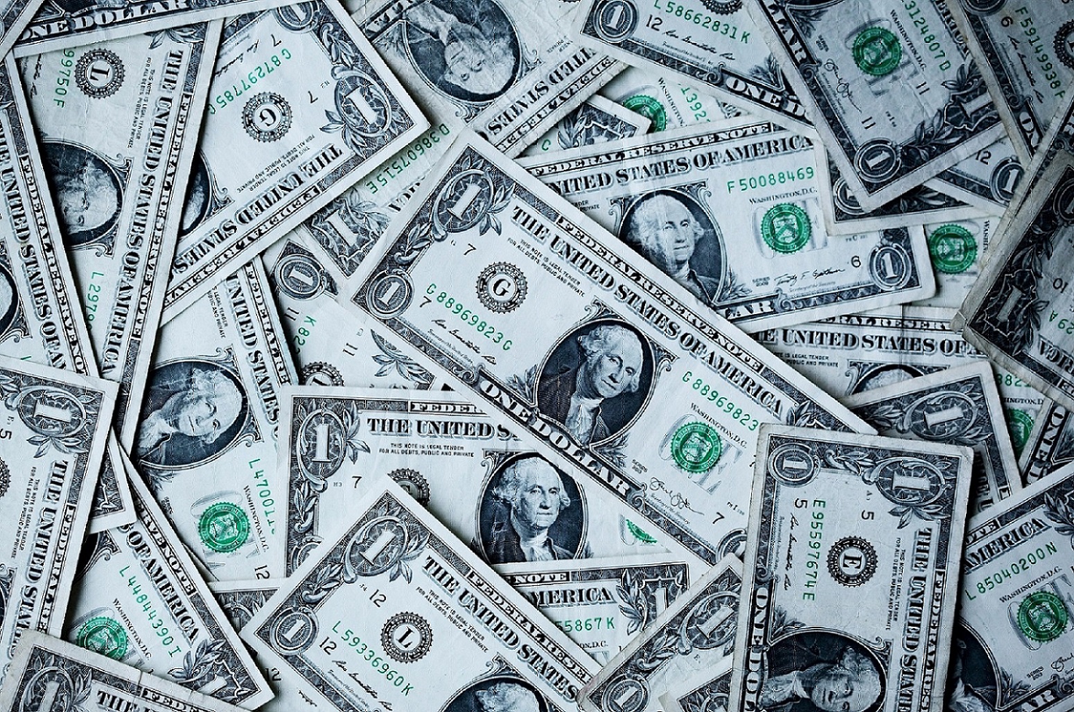 Scattered one-dollar bills covering a flat surface, representing currency in a financial context.