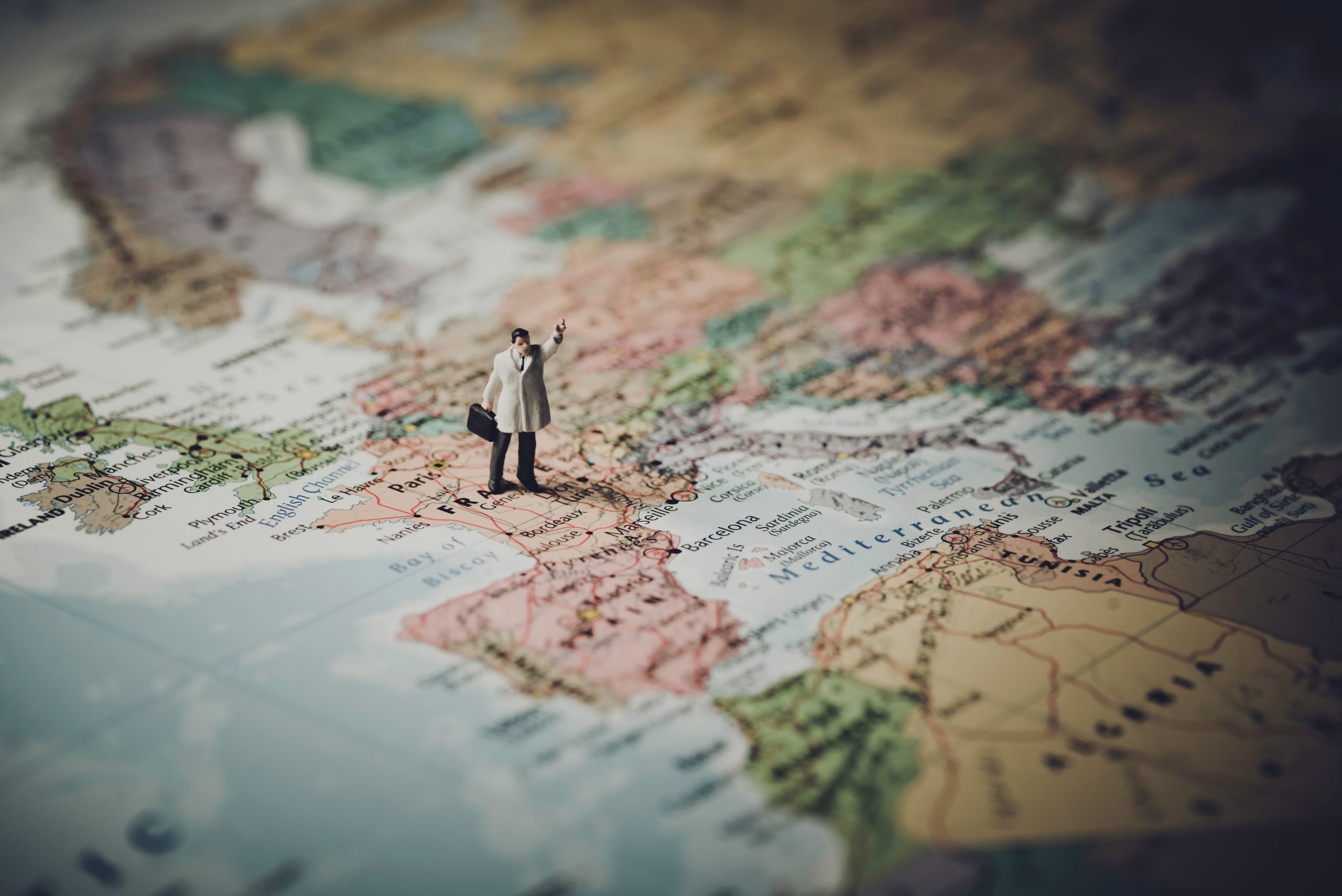 Business professional in a suit holding a briefcase, standing on a detailed map of Europe.