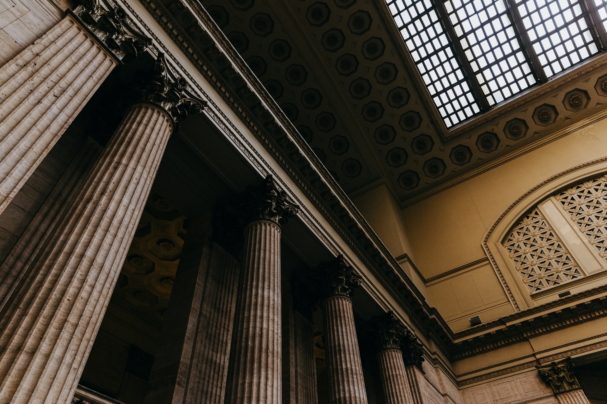 Courtroom interior featuring large columns and ornate ceiling details. Light filters through skylights above.