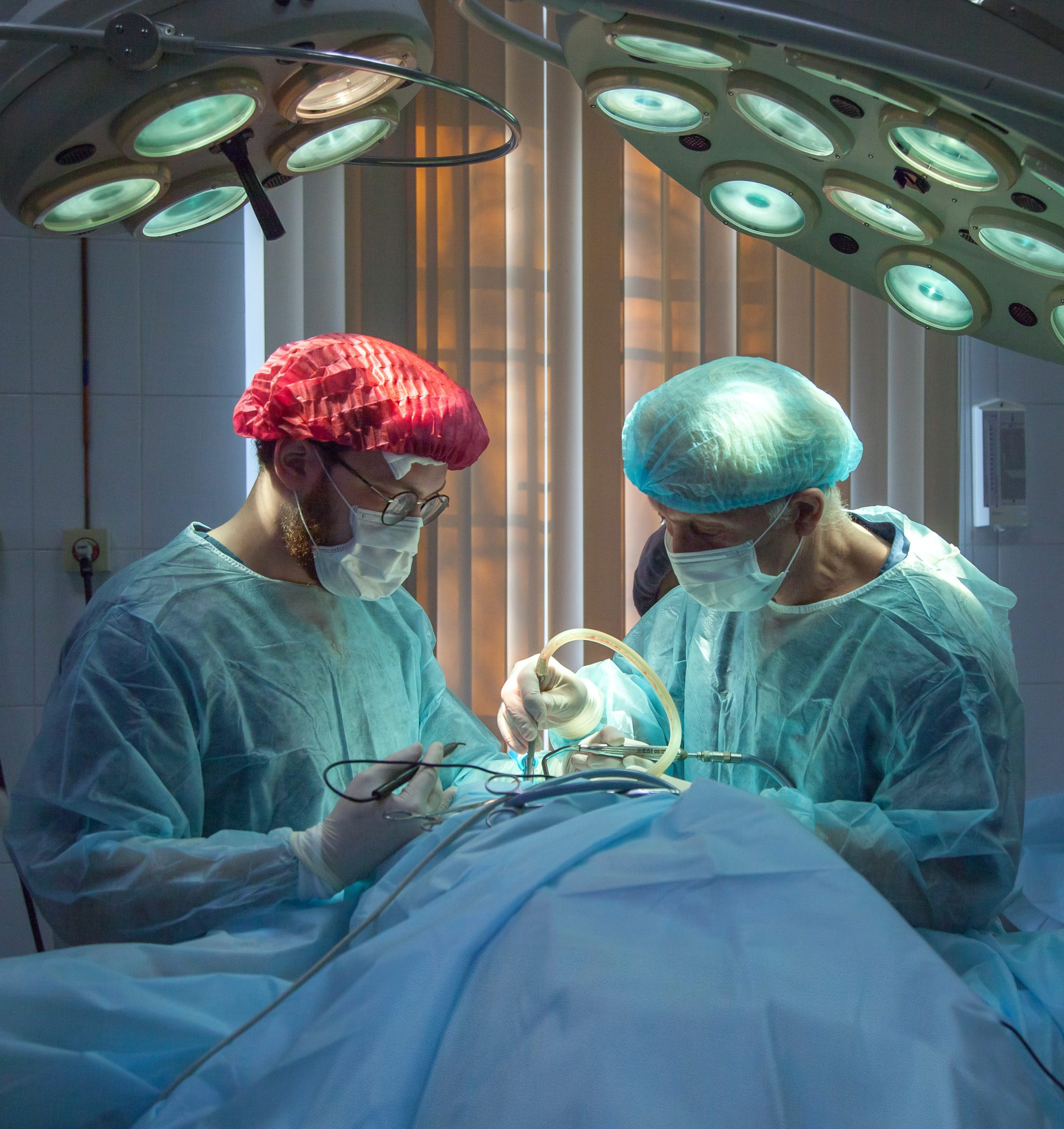 Surgeons performing an operation while wearing surgical masks and gowns in an operating room.