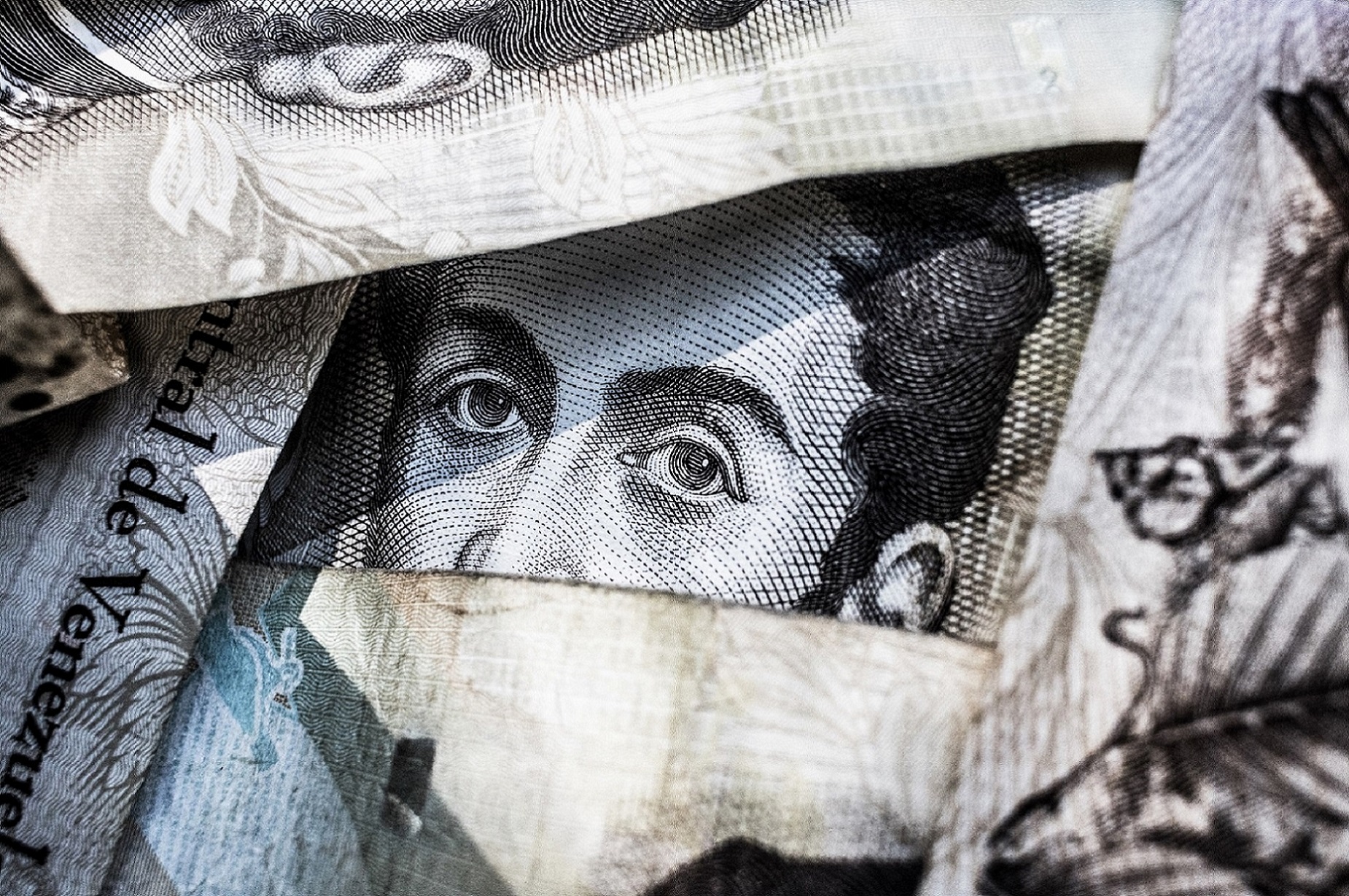 Close-up of various banknotes overlapping, featuring intricate details and patterns of Venezuelan currency.