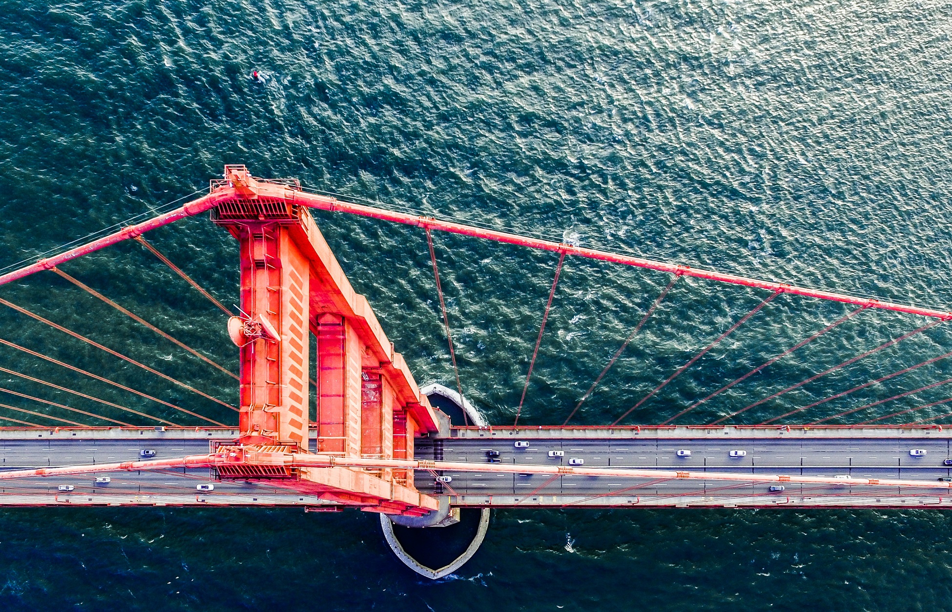 Aerial view of a large suspension bridge spanning a body of water with vehicles crossing.