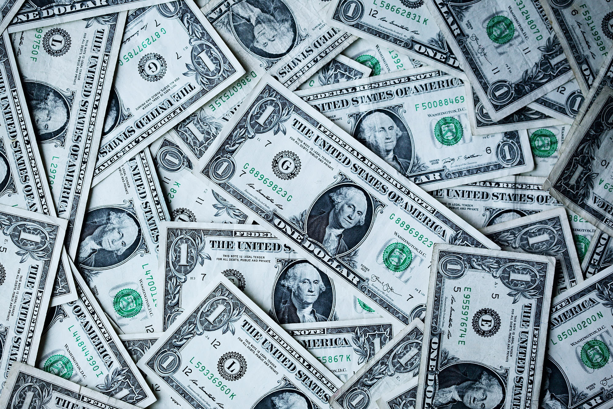 Scattered U.S. one-dollar bills on a flat surface, representing currency in legal and financial contexts.