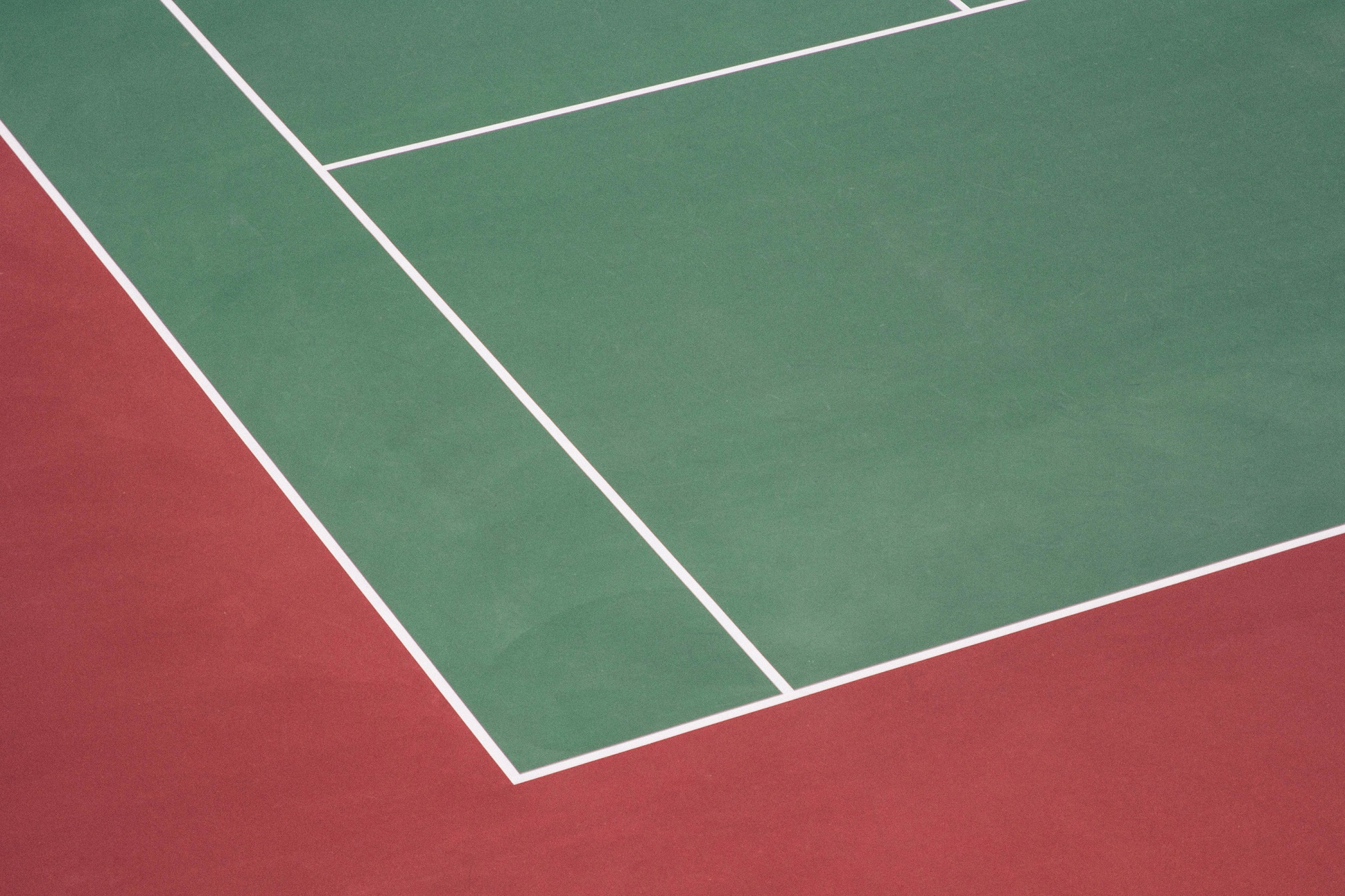 Tennis court with green and red surfaces and white boundary lines.