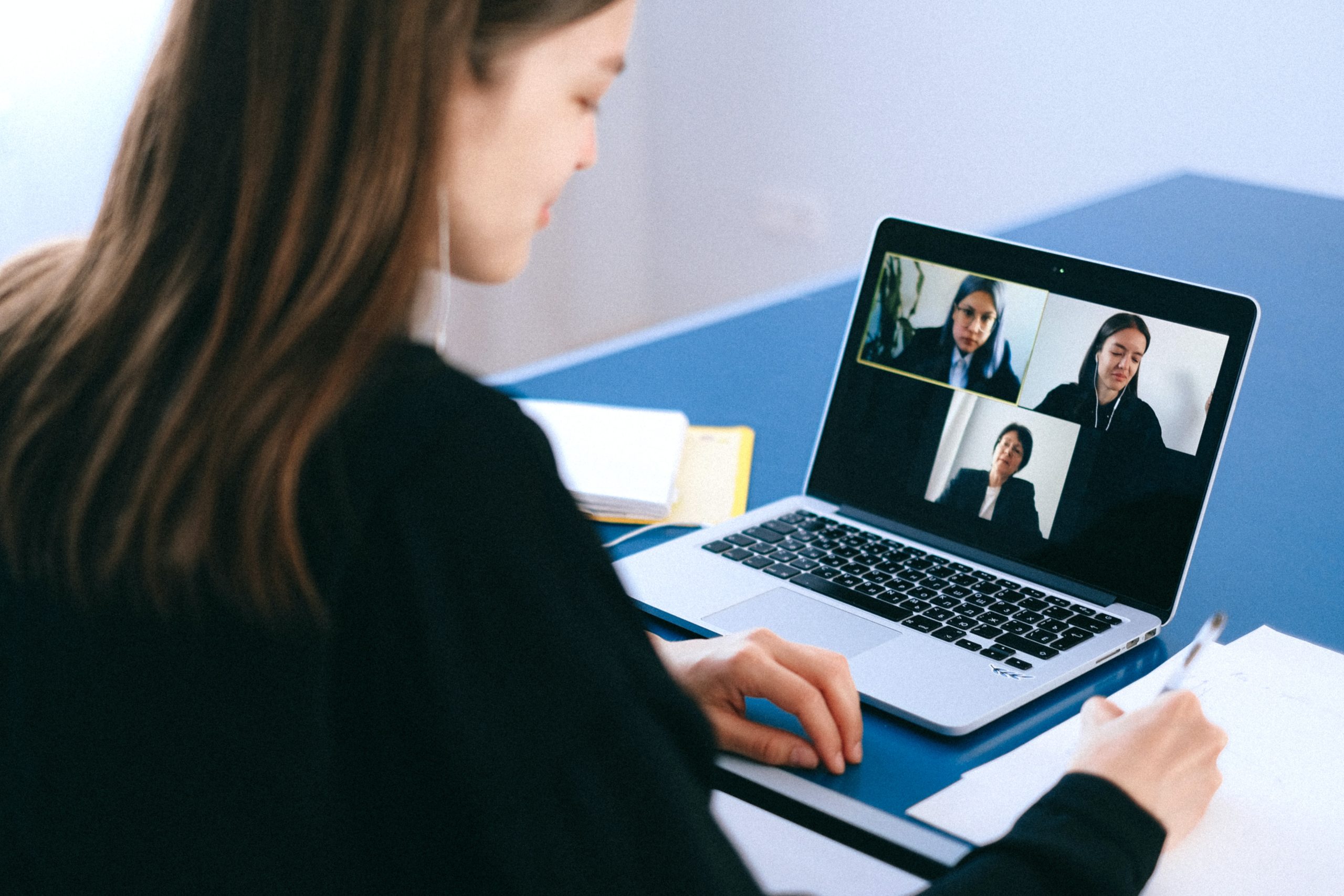 Attorney participating in virtual meeting with colleagues, reviewing notes while discussing legal matters.