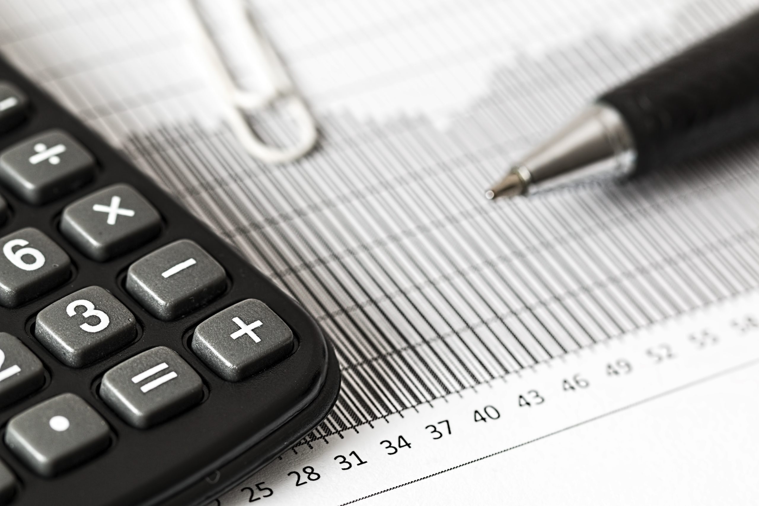 Calculator beside a pen and a graph paper showing statistical data, implying financial analysis in a legal context.