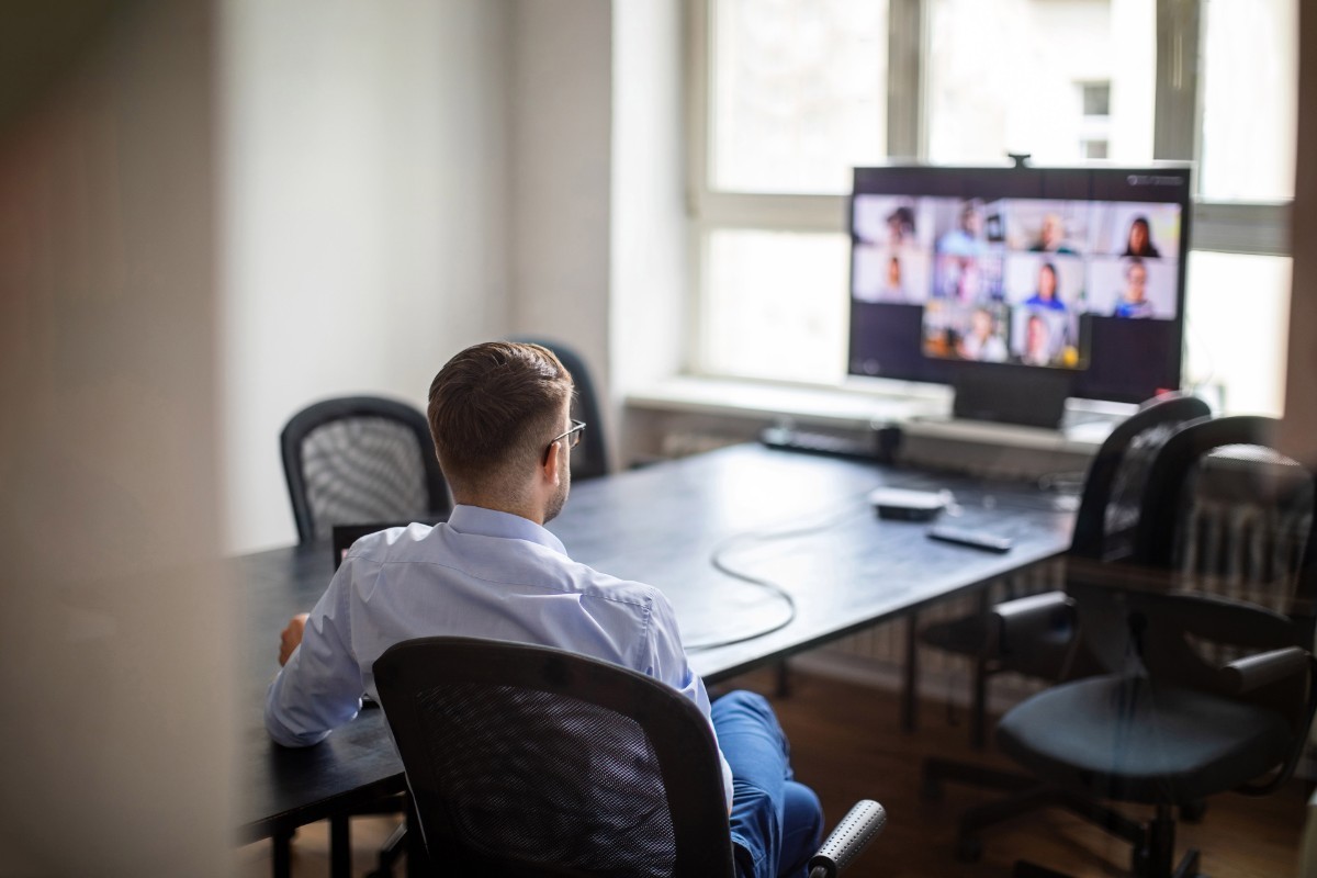 Attorney participating in a virtual meeting, seated at a conference table with multiple participants on screen.
