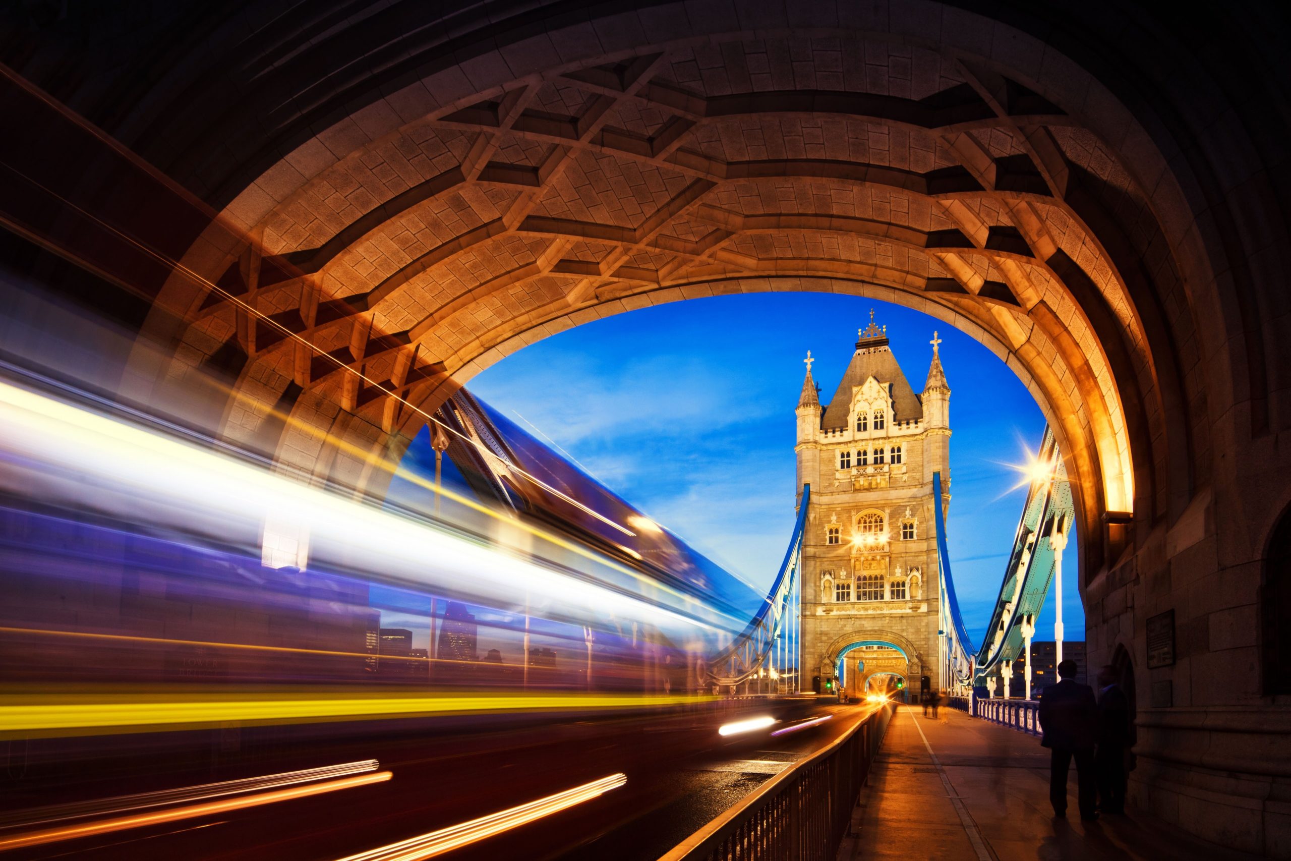 Tower Bridge illuminated at dusk with traffic passing through, showcasing an iconic London landmark.