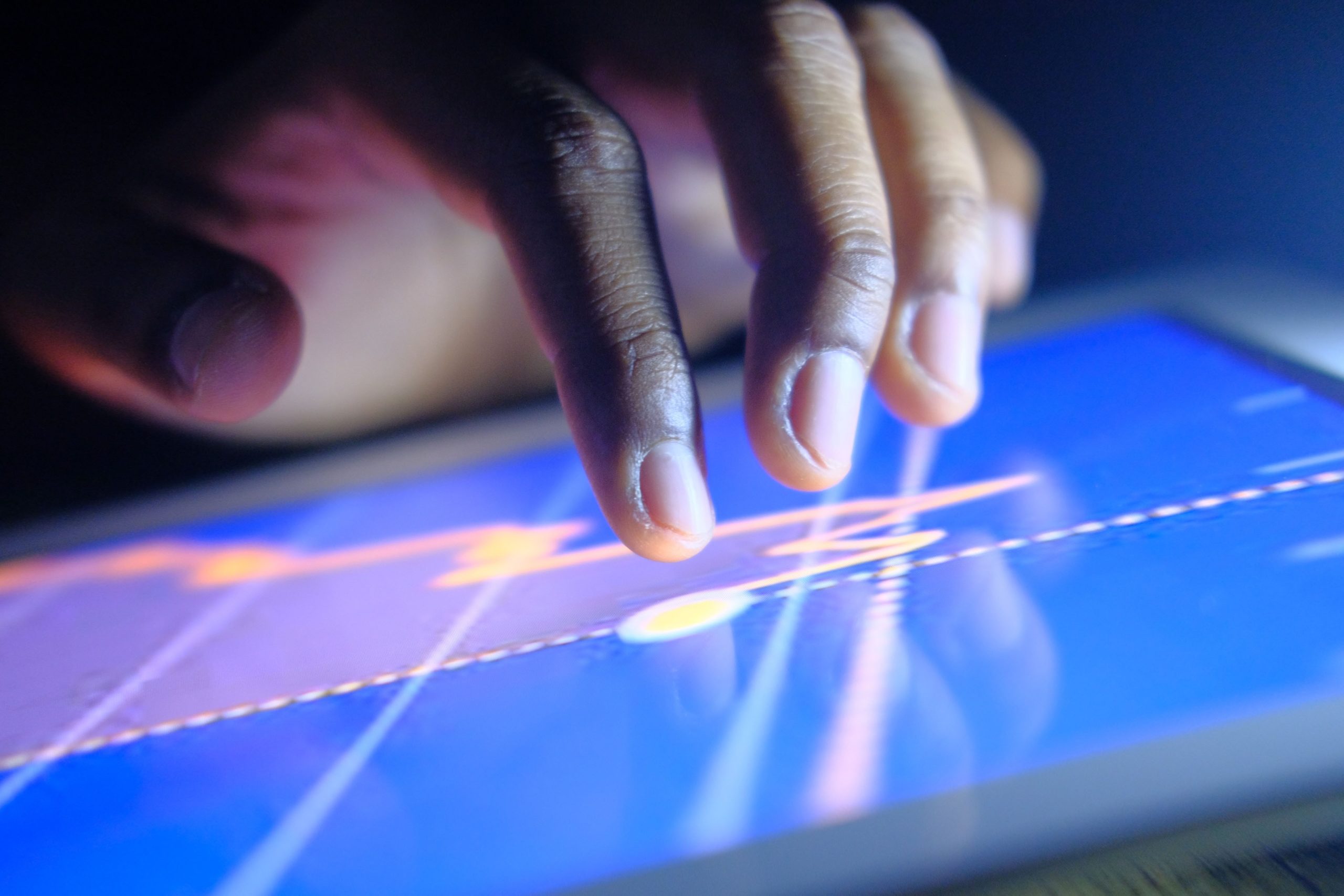 Hand interacting with a touchscreen displaying legal charts and data in a darkened environment.