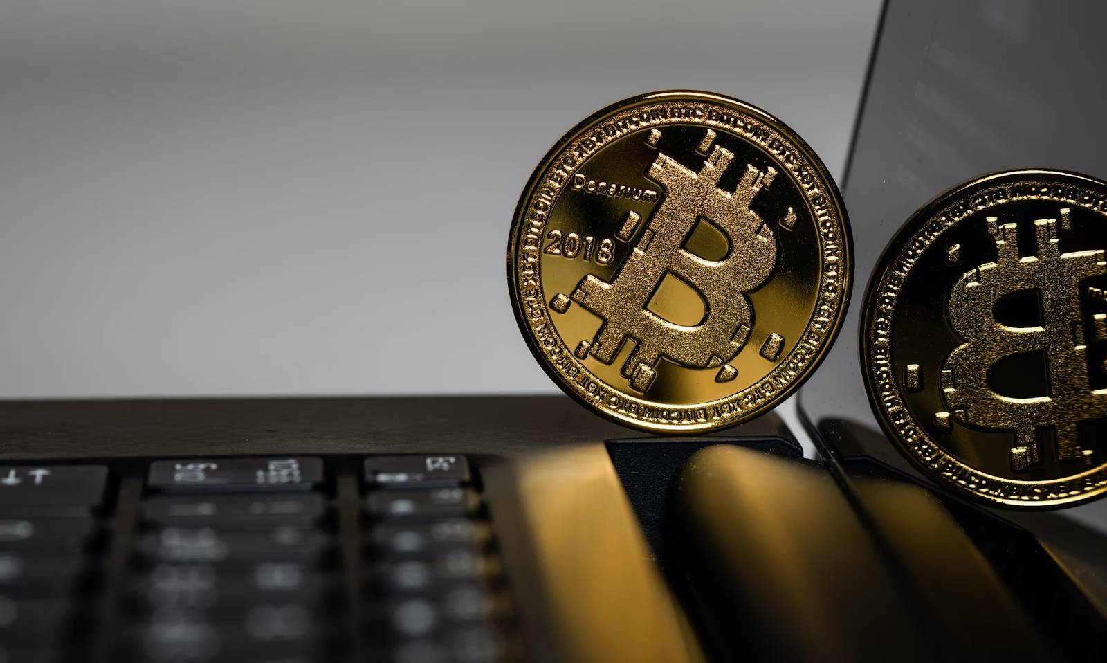 Bitcoin coins placed next to a laptop keyboard, symbolizing digital currency in financial discussions.