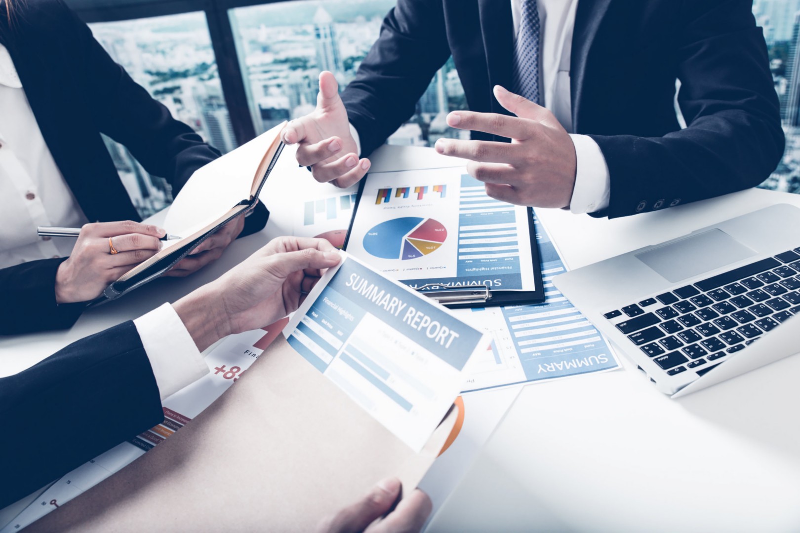 Business professionals discussing financial data with reports and charts on a conference table