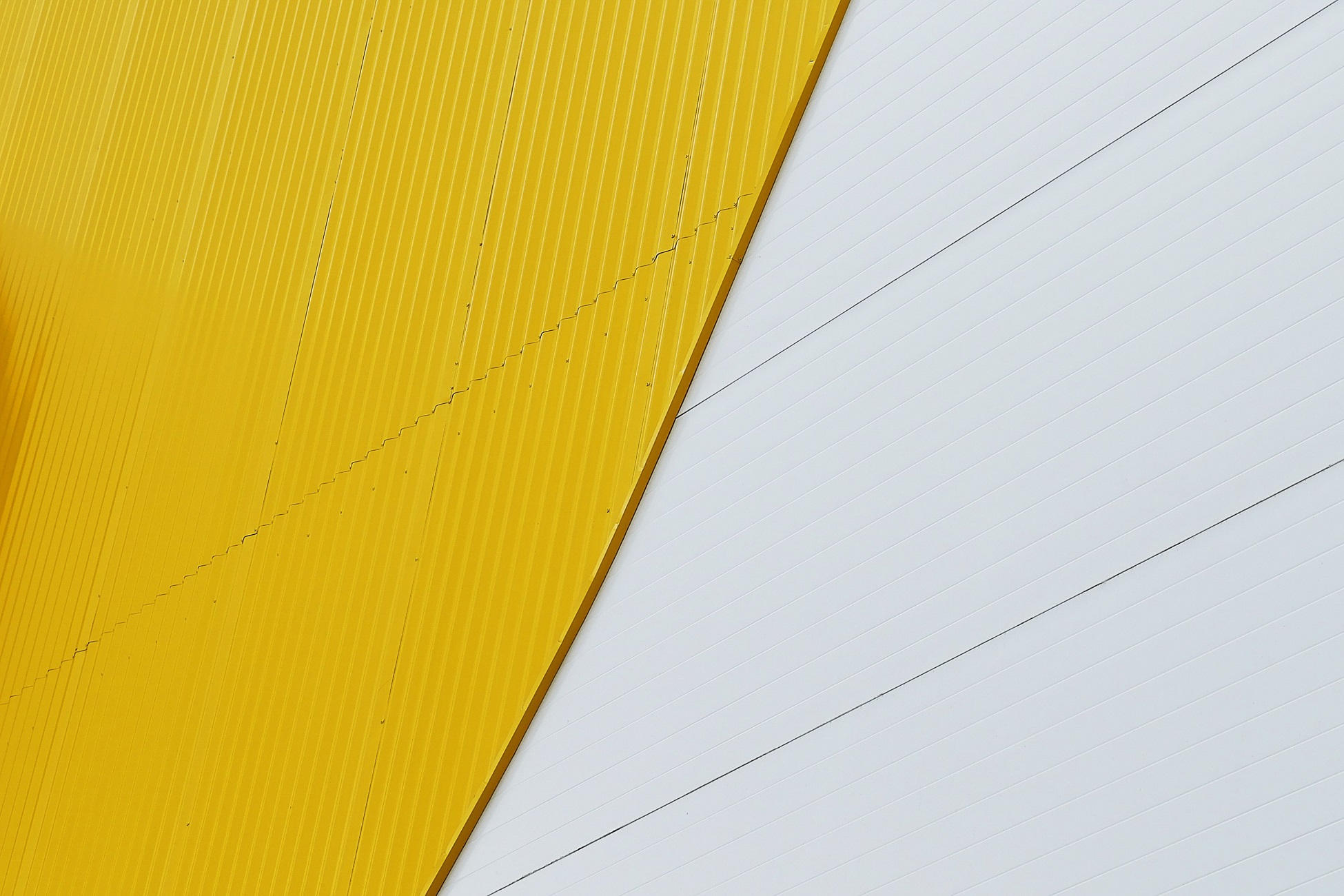 Abstract pattern of yellow and white metal panels on a building exterior.