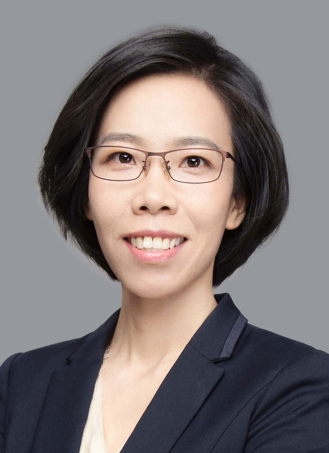 Legal professional smiling, wearing glasses and a dark blazer, with a neutral background in a business setting.