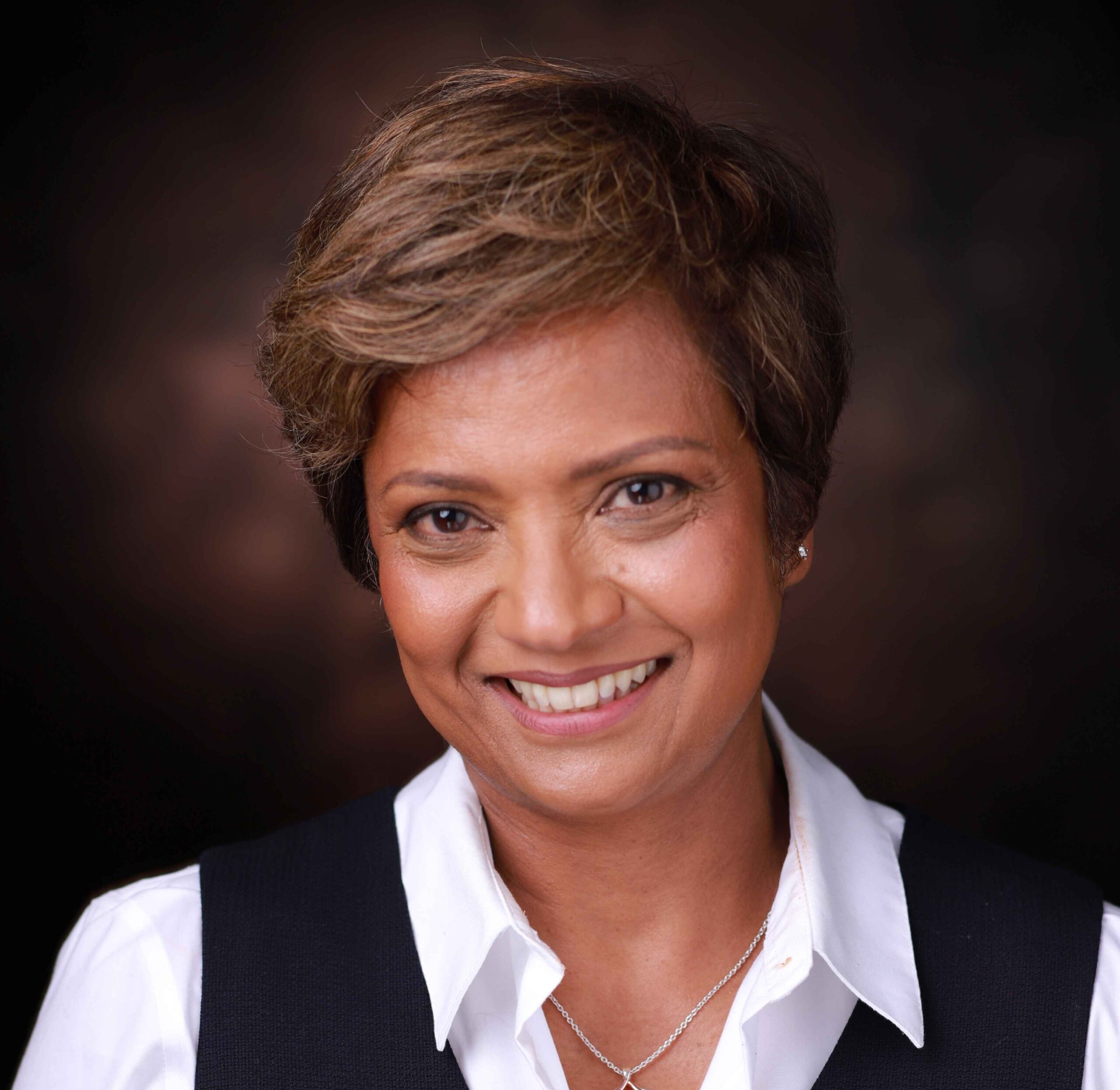 Legal professional smiling in a black vest over a white shirt, against a neutral background.