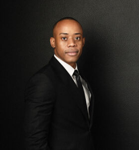Professional man in a suit against a dark background, presenting a confident appearance.