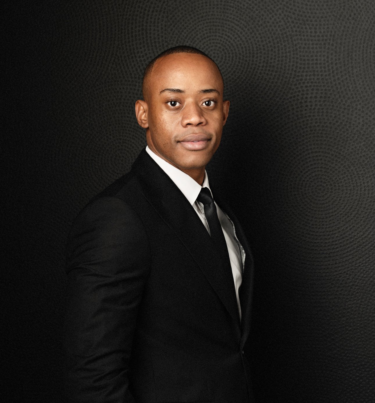 Professional man in a suit against a dark background, presenting a confident appearance.