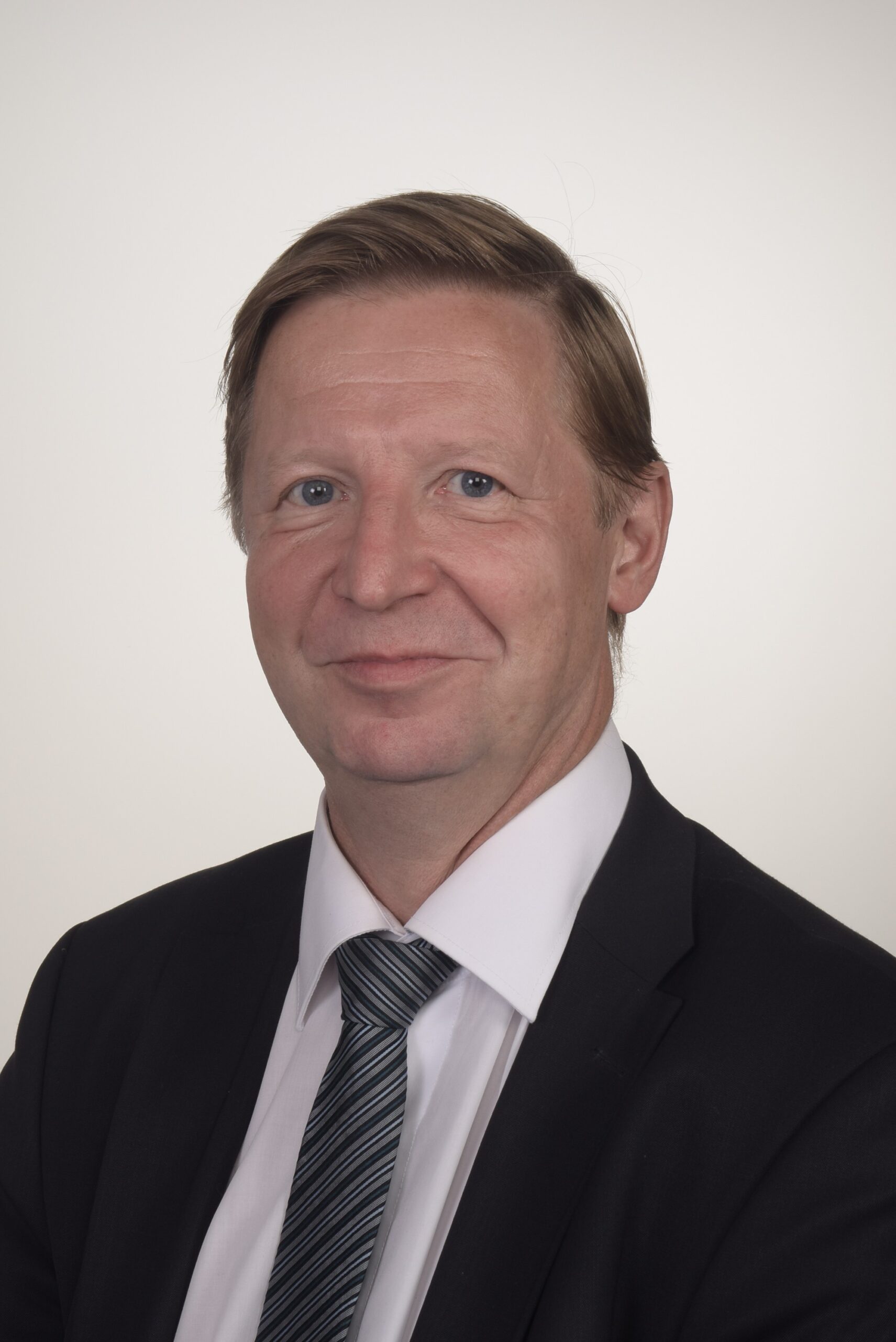 Lawyer in a suit with a tie, posing for a professional headshot against a neutral background.