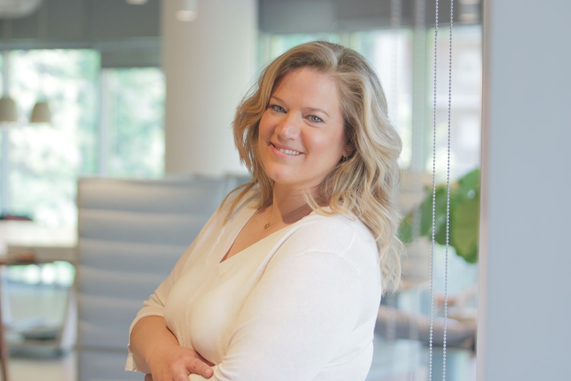 Attorney with a friendly demeanor standing with arms crossed in a modern office environment.