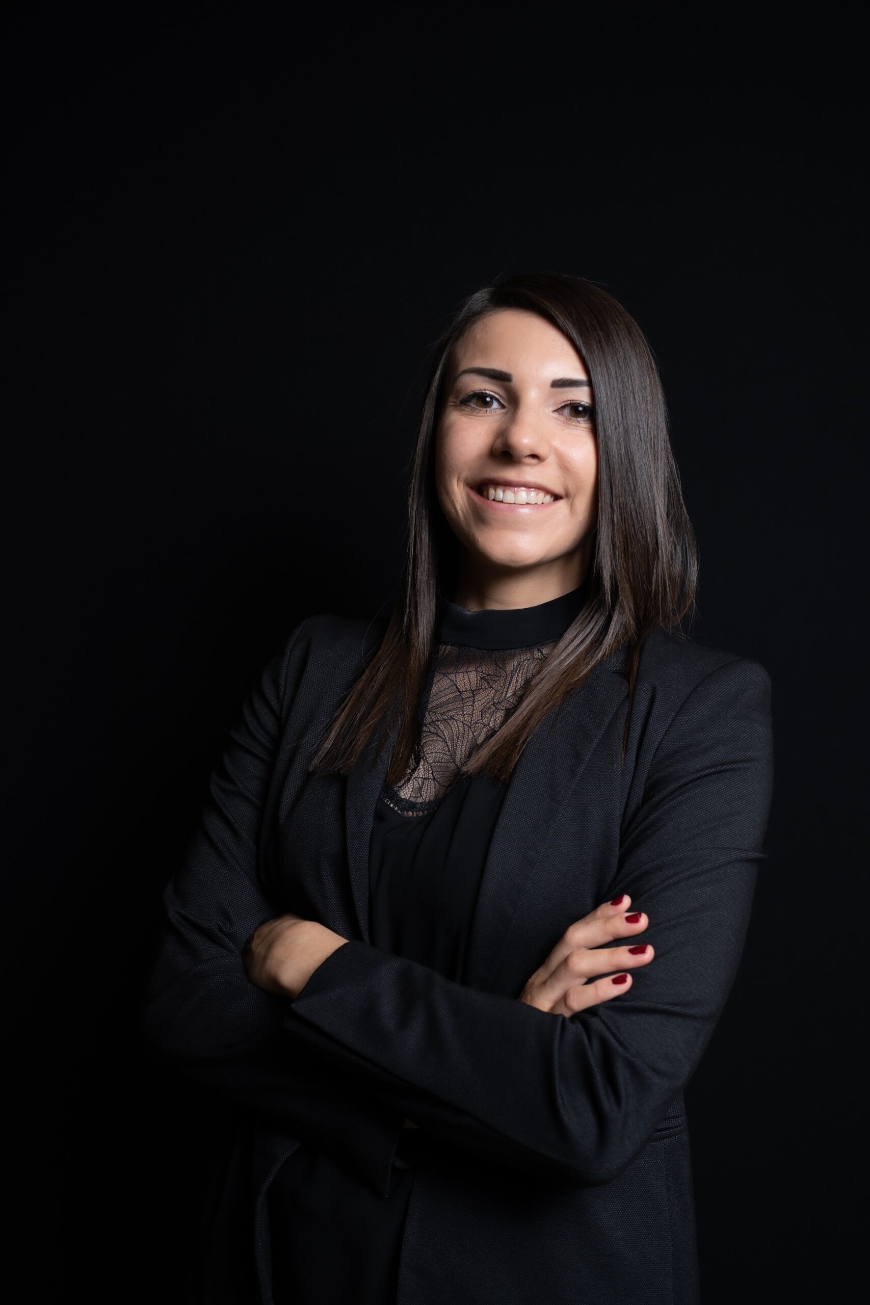 Legal professional smiling with arms crossed against a black background.