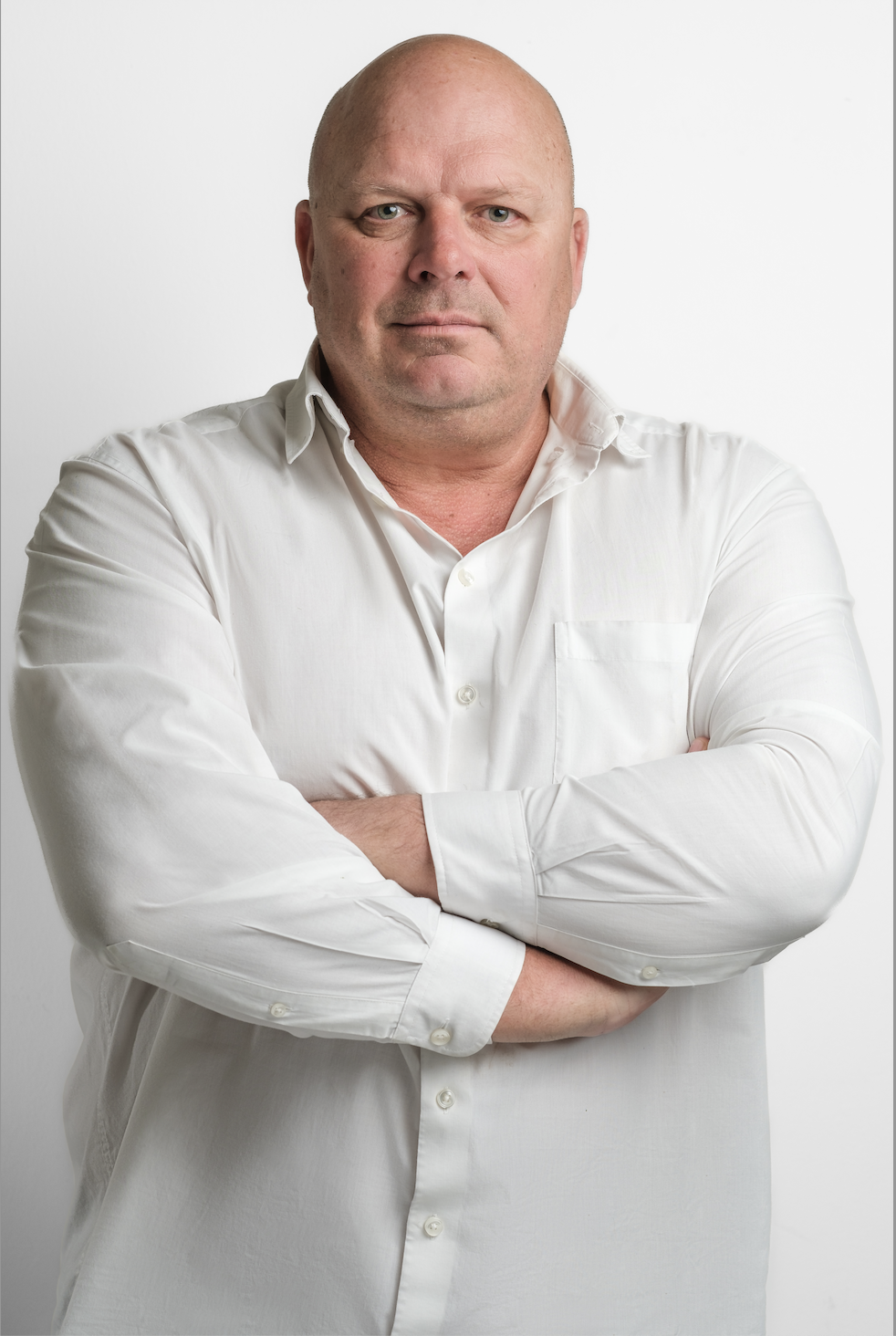 Professional man in a white shirt standing with arms crossed against a plain background.