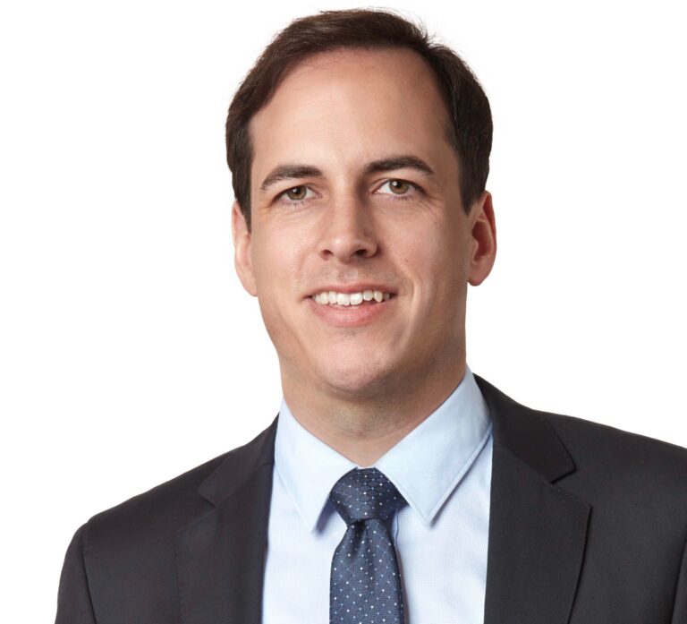 Lawyer in a suit smiling, posed against a neutral background.