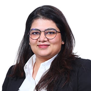 Lawyer smiling and wearing glasses, dressed in a black suit with a white shirt, suitable for a professional legal setting.