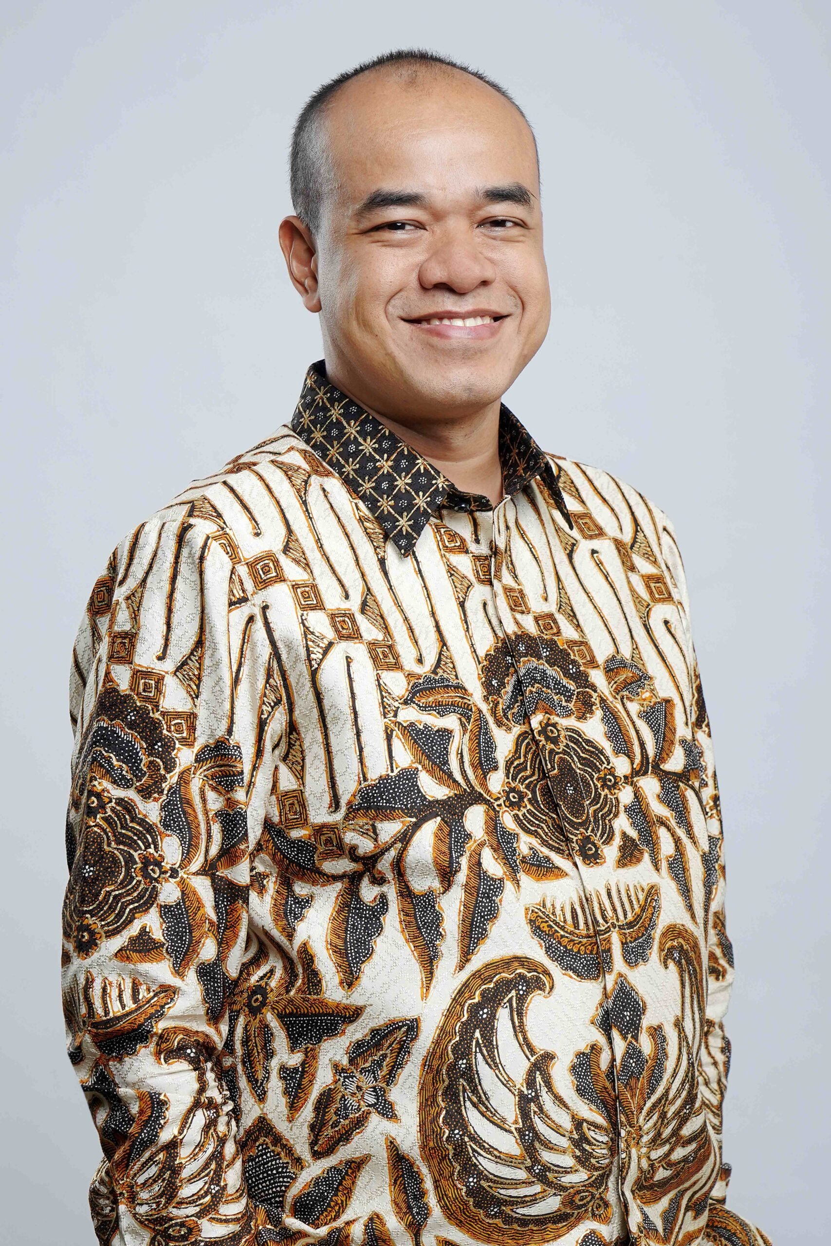 Male legal professional smiling, wearing a patterned shirt in a neutral background.