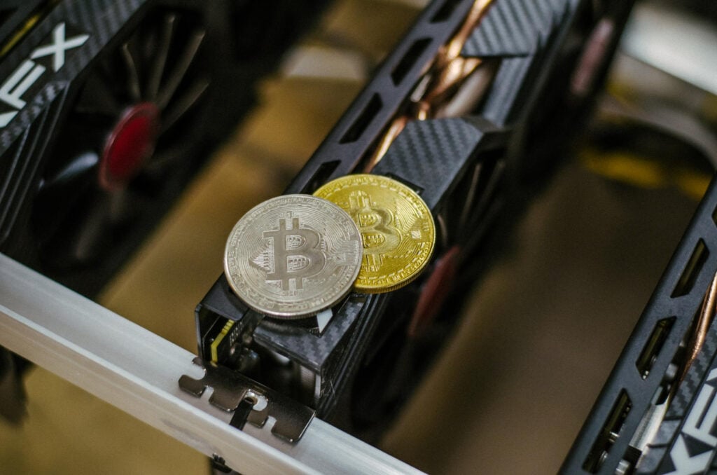 Home - One Silver And One Gold Bitcoin Sitting On Top Of An Electronic Board - Global Law Experts