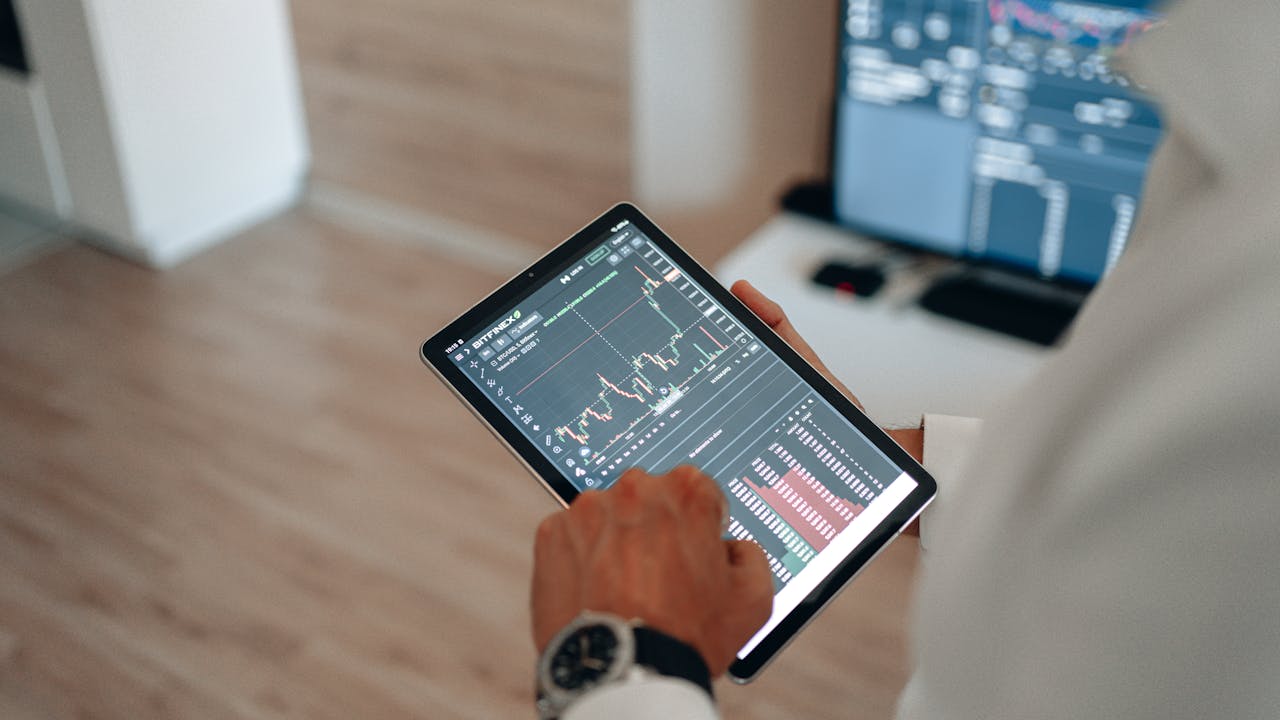 Professional analyzing financial data on a tablet in a modern office environment.
