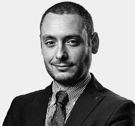 Attorney posing confidently in a suit with arms crossed, against a plain background.