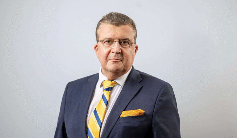 Legal professional in a suit, standing confidently against a neutral background.