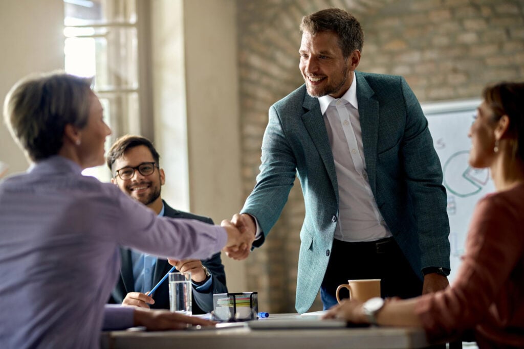 Home - Two People Shaking Hands In A Business Meeting - Global Law Experts