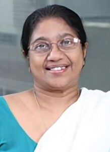 Legal Professional Smiling, Wearing Traditional Attire, Posing Against A Blurred Background.