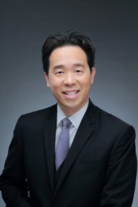 Lawyer in a suit smiling confidently against a neutral background.