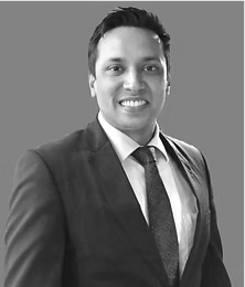 Smiling lawyer in a suit standing against a neutral background.