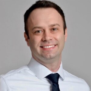 Lawyer smiling confidently in a professional setting with a neutral background.