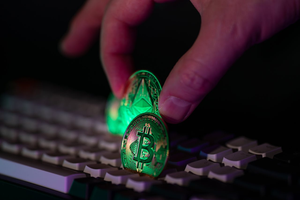 Hand placing cryptocurrency coins on a computer keyboard, highlighting digital finance themes.