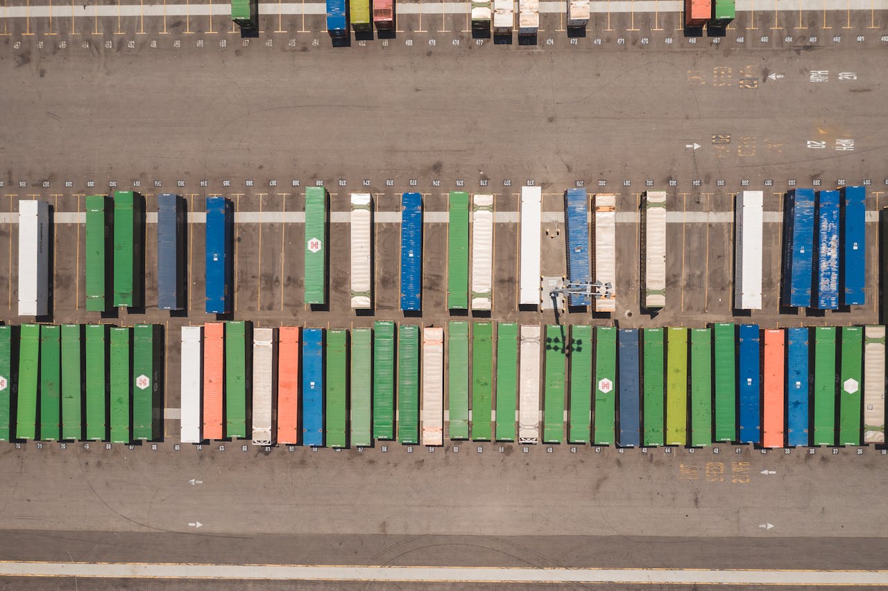Aerial view of a shipping yard with rows of colorful cargo containers arranged in organized patterns.