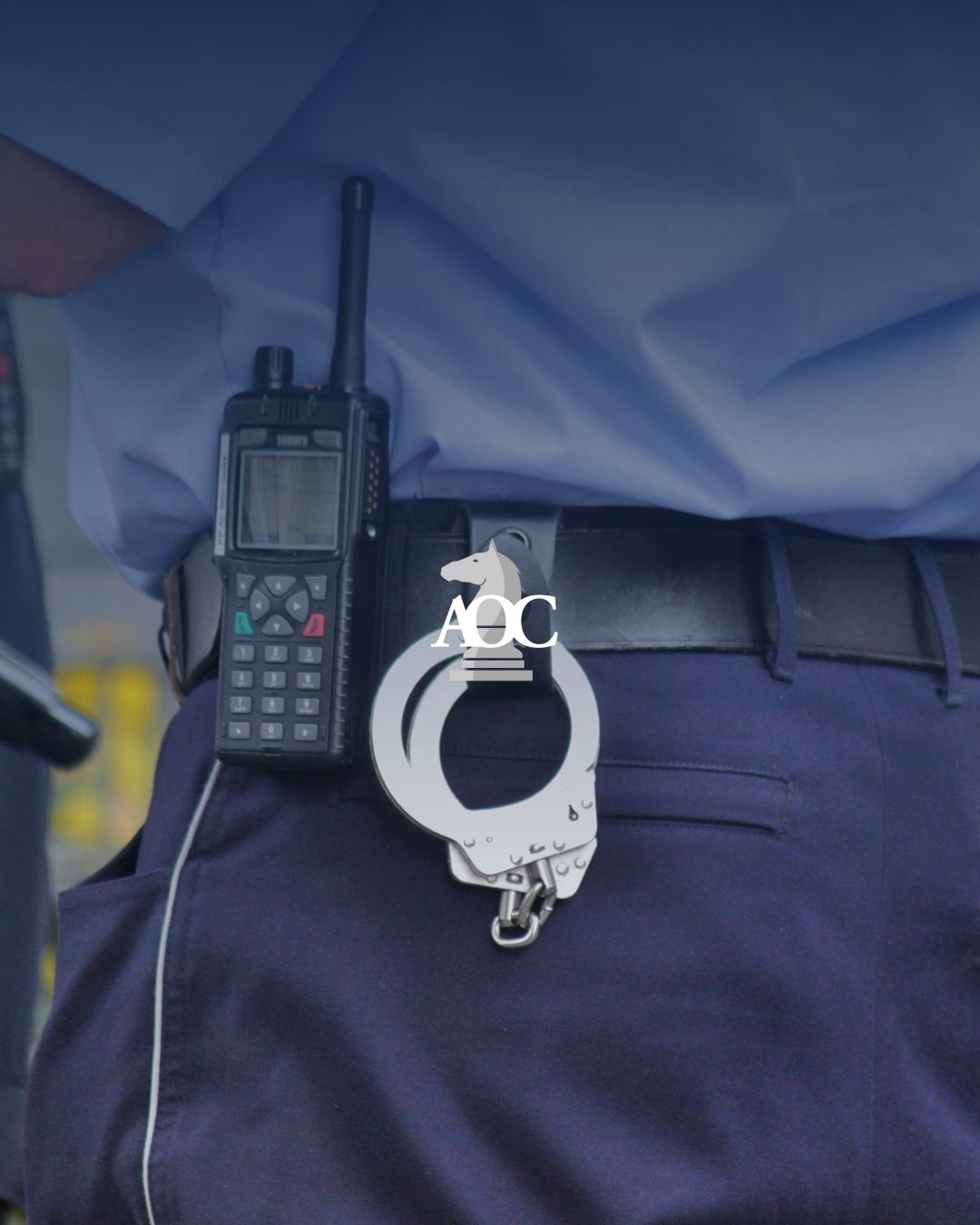 Law enforcement officer's belt with handcuffs and a radio in a security context.