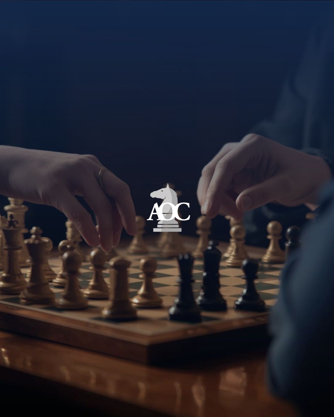 Hands moving chess pieces on a board in a strategic game setting with a blurred background.