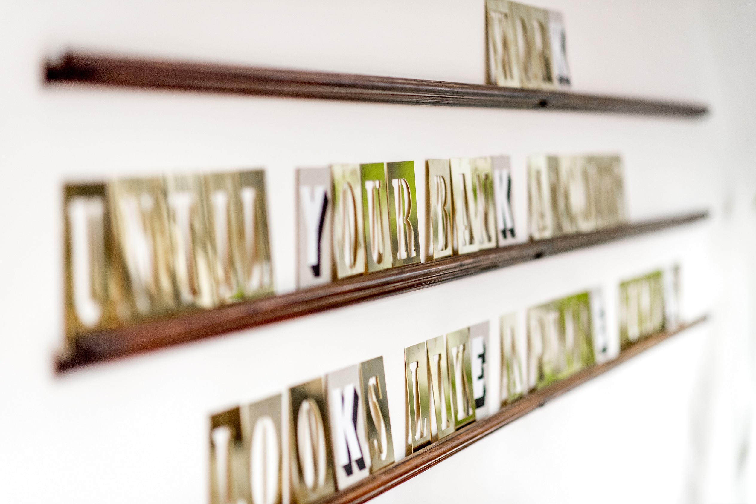 Decorative wall art displaying motivational phrases arranged on shelves in a bright interior space.