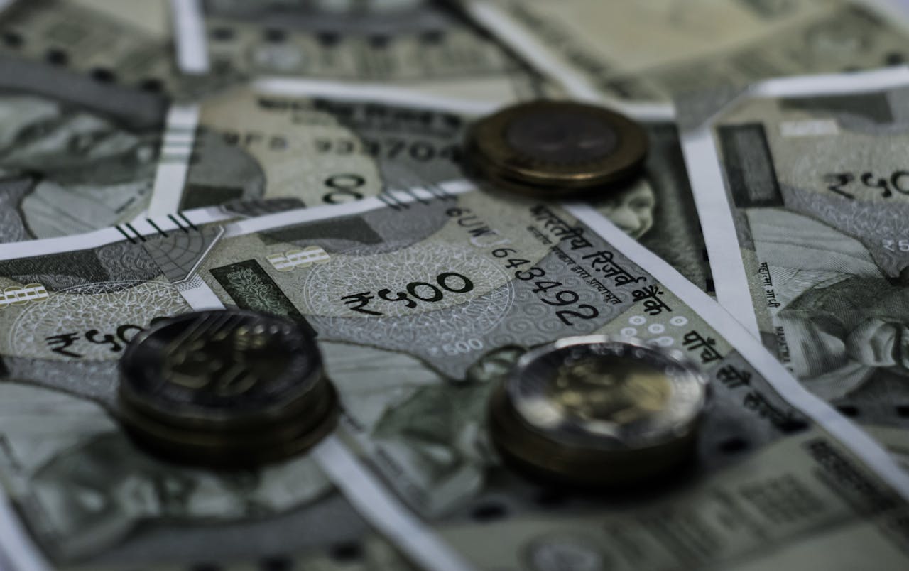 Indian currency notes and coins arranged in a scattered layout on a surface.